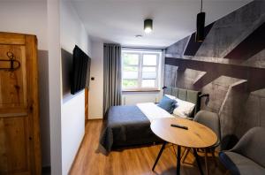 1 dormitorio con cama, mesa y ventana en Aparthotel Krzywa, en Katowice