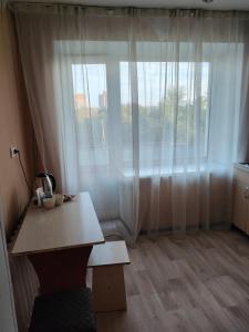 Zimmer mit einem Tisch und einem großen Fenster in der Unterkunft Galeto 22 Apartments in Semei