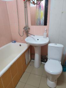 a bathroom with a toilet and a sink and a bath tub at Galeto 22 Apartments in Semey
