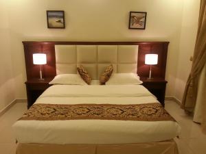 a bedroom with a large bed with two lamps at Lara Al Jawf Hotel Apartments in Arar