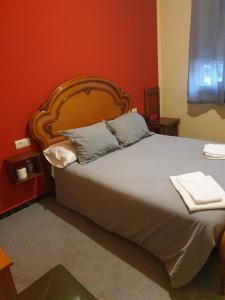 a bedroom with a large bed with a wooden headboard at A Concha in Lavacolla