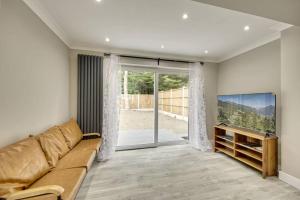 Little BursteadにあるLuxurious quiet 5-bedroom house.のソファと大きな窓のあるリビングルーム