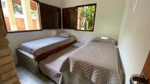 two beds in a small room with two windows at A Casa de Ponta-Simplicidade e Requinte -Estrutura Completa a 150m da praia in Maragogi