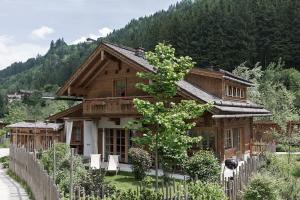 a wooden house with a fence in front of it at Feriendorf Holzlebn in Grossarl