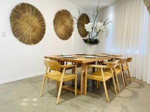 a dining room with a wooden table and chairs at KozyGuru / Botany / 3 Bedroom Designer Apt / NBO003 in Sydney