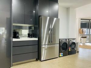 a kitchen with a stainless steel refrigerator and a dishwasher at KozyGuru / Botany / 3 Bedroom Designer Apt / NBO003 in Sydney