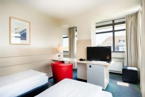 a hotel room with two beds and a desk with a computer at Enjoy Hotel am Studio in Berlin