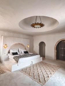 a white bedroom with a large bed and a chandelier at Dar Naël in Houmt Souk