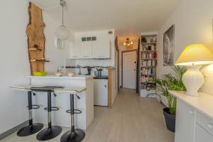 a kitchen with white cabinets and bar stools at Studio vue sur l'océan in Anglet