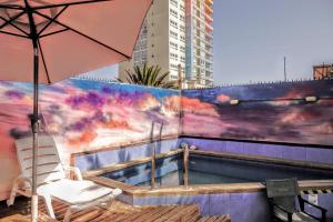 un patio con sombrilla, silla y piscina en Aotea Hostel Iquique, en Iquique