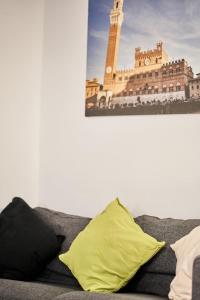 a couch with a yellow pillow and a picture of a clock tower at Casa Monelli in Siena