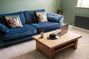 a living room with a blue couch and a table with a laptop at Cosy Lake District Cottage in Staveley