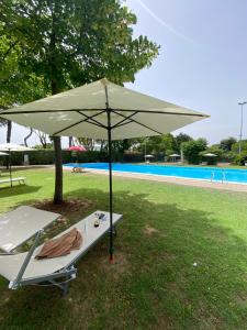 - une table avec un parasol à côté de la piscine dans l'établissement Villetta 8 - Piscina e campi da gioco - Narramondo Villas, à Giulianova