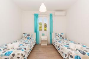 two beds in a room with blue curtains and a window at Solar Santo Antonio in Palmela