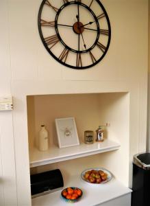 a large clock hanging above a counter with bowls of fruit at Braidwood in Castle Douglas