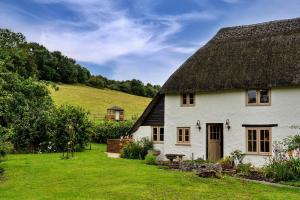 a white cottage with a thatched roof at Finest Retreats - Manor Cottage in Winterborne Stickland