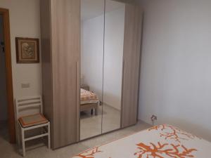 - un miroir dans une chambre avec un lit et une chaise dans l'établissement Appartamento In Riva Al Mare con Posto Auto E Disponibilità Bicicletta, à Mascali