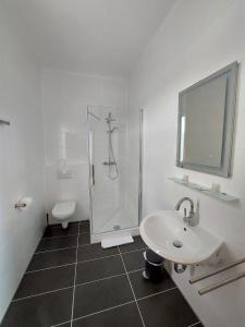 biała łazienka z prysznicem i umywalką w obiekcie Brauereigasthof Schlüsselkeller w mieście Giengen an der Brenz