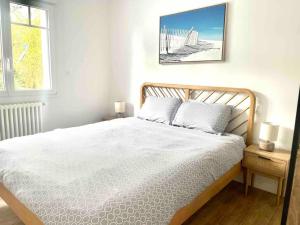 ein Schlafzimmer mit einem weißen Bett mit zwei Lampen und einem Fenster in der Unterkunft Villa Nolaene, 8-9 pers, Piscine, Calme et Moderne in Gujan-Mestras