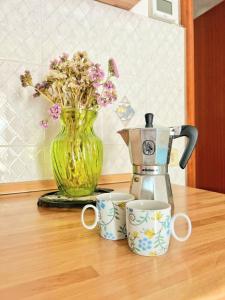 Un jarrón con flores y dos tazas en una mesa. en Villa D'Agati, en San Giorgio