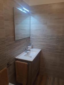 La salle de bains est pourvue d'un lavabo et d'un miroir. dans l'établissement Appartamento In Riva Al Mare con Posto Auto E Disponibilità Bicicletta, à Mascali