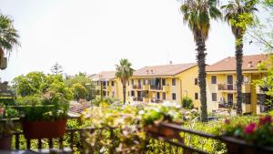 - une vue sur un bâtiment avec des palmiers et des fleurs dans l'établissement AV Apartment, à Aci Castello