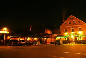 un edificio iluminado con coches estacionados frente a él por la noche en Pension Herman, en Rudník