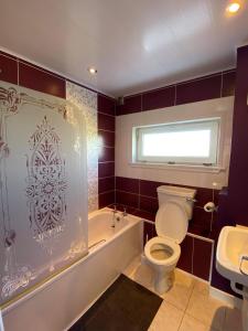 a bathroom with a toilet and a tub and a sink at Seasgair House in Balivanich