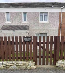 a sign on a wooden fence in front of a house at Seasgair House in Balivanich