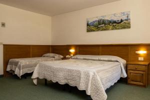 a room with two beds and a painting on the wall at Wellness Hotel Dolomia in Soraga