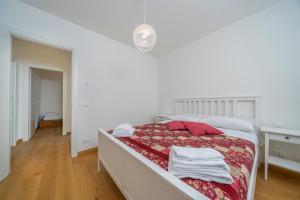 um quarto branco com uma cama com almofadas vermelhas em The House of Antonietta em Udine