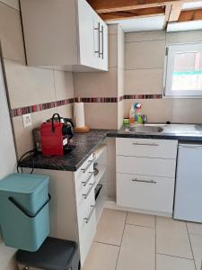 eine kleine Küche mit weißen Schränken und einem roten Koffer in der Unterkunft "Les Echalas" Appartement indépendant avec cuisine en Lavaux Unesco in Chexbres