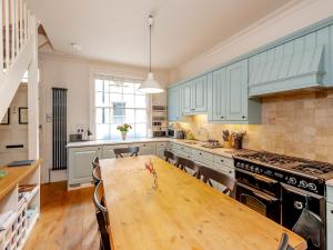 een keuken met blauwe kasten en een houten tafel bij Pass the Keys Luxury City Centre House in Bath