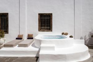 a hot tub in a white room with two benches at On An Island suites & apartments - Fira in Fira