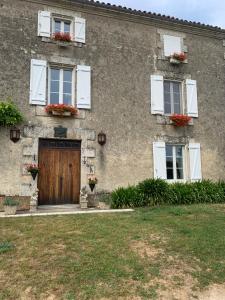 uma casa de pedra com uma porta de madeira e janelas em NO5 Chambre D'hotes em Courcôme