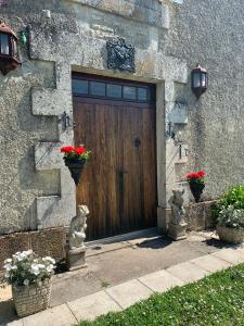 a wooden door with red flowers in a stone building at NO5 Chambre D'hotes in Courcôme
