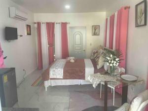1 dormitorio con 1 cama con cortinas rojas y mesa en Royal Terrace V (Duque), en San Felipe de Puerto Plata