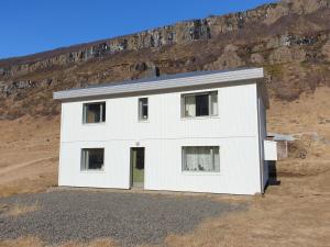 een wit huis voor een berg bij Hóll in Óbyggðasetur