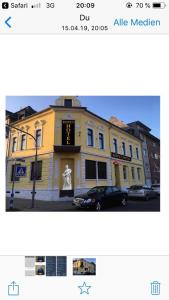 un edificio amarillo con un reloj delante en Ferienwohnung&Aparts By kispet group hotels in Oberhausen en Oberhausen