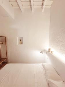 een witte slaapkamer met een bed en een licht aan de muur bij Casa Concha Apartamentos in Calella de Palafrugell