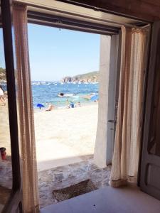 an open door to a beach with people on the beach at Casa Concha Apartamentos in Calella de Palafrugell
