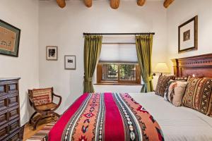 a bedroom with a bed and a chair and a window at Amor - Historic Adobe, Amazing Location in Santa Fe