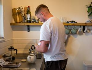 a man standing in a kitchen preparing food at Daisy Bank Camp in Hebden Bridge