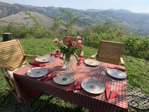 a picnic table with plates and a vase of flowers at Casale IL SAMBUCO sui colli bolognesi in San Lazzaro di Savena
