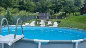 a swimming pool with a bunch of chairs in a yard at Bârlogul Urșilor in Şinca Veche