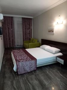 a bedroom with a bed and a green chair at ÇAMLIK PANSİYON in Antalya