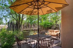 uma mesa e cadeiras com um guarda-sol num pátio em Artesano em Santa Fe