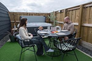a man and a woman sitting at a table on a patio at Glengolly Getaways in Thurso