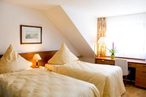 a bedroom with two beds and a desk and a window at Hotel Kölner Hof Refrath in Bergisch Gladbach