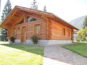 a log cabin with a grassy yard in front of it at Chalet Camping Faè 2 in Madonna di Campiglio